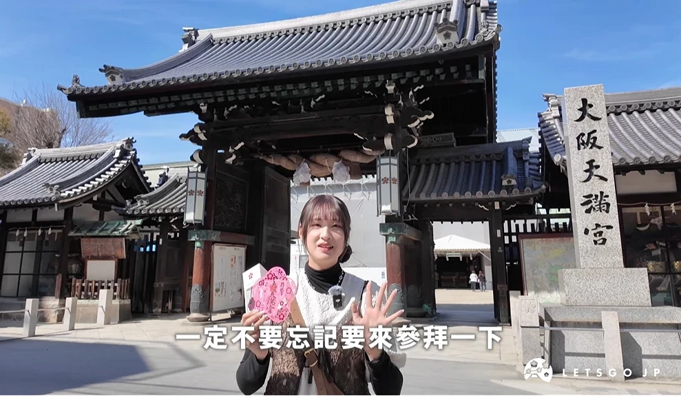 主持人站在大阪天滿宮門口介紹