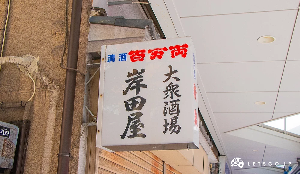 岸田屋大眾酒場招牌 老舊建築牆面掛著白色方形燈箱,上方寫有「清酒 百万両 大衆酒場 岸田屋」。