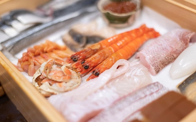 木製展示箱中鋪冰,陳列蝦、烏賊、貝類等新鮮海鮮食材
