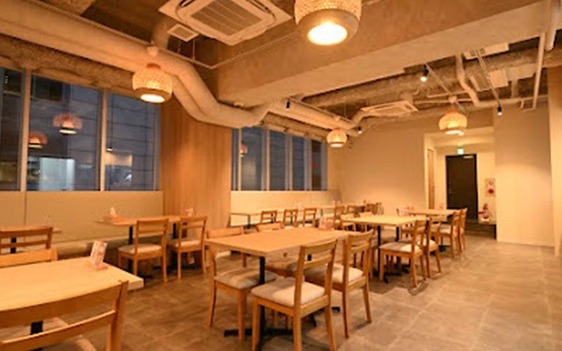 餐廳內部,木製桌椅排列整齊,藤編燈罩吊燈,採光明亮