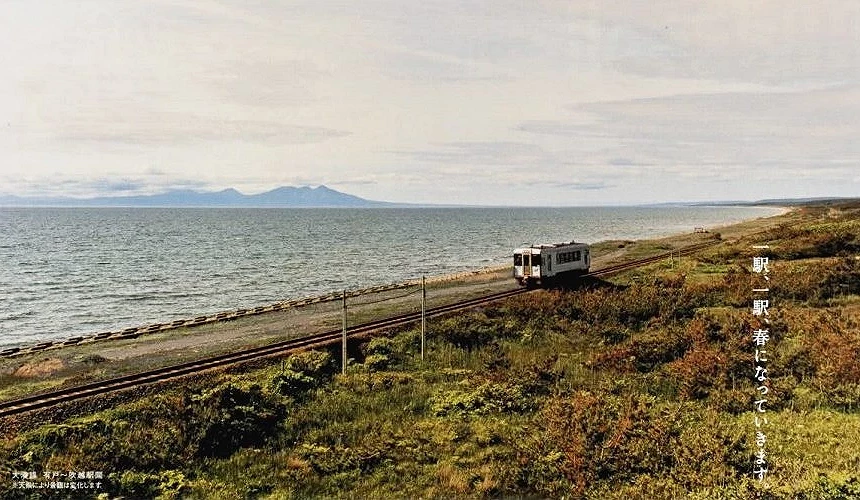 單節列車沿海岸鐵道行駛,遠方可見山影