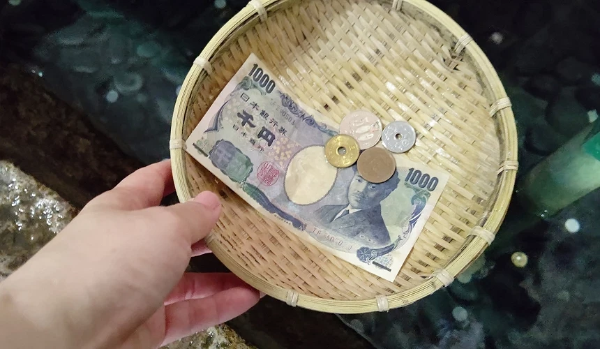 手持的竹籃裡裝著一千日圓及零錢