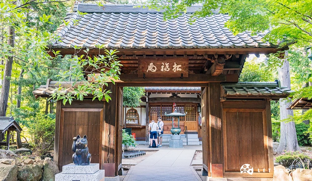 寺廟面前有個木拱門,有隻黑色貓咪在右前方招福