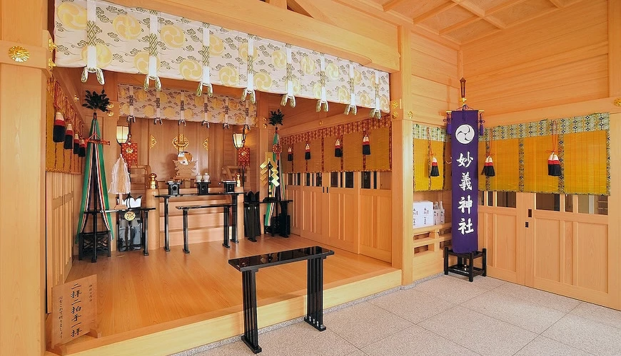妙義神社拜殿內部,木質空間明亮,設有祭壇、奉納物與參拜區。