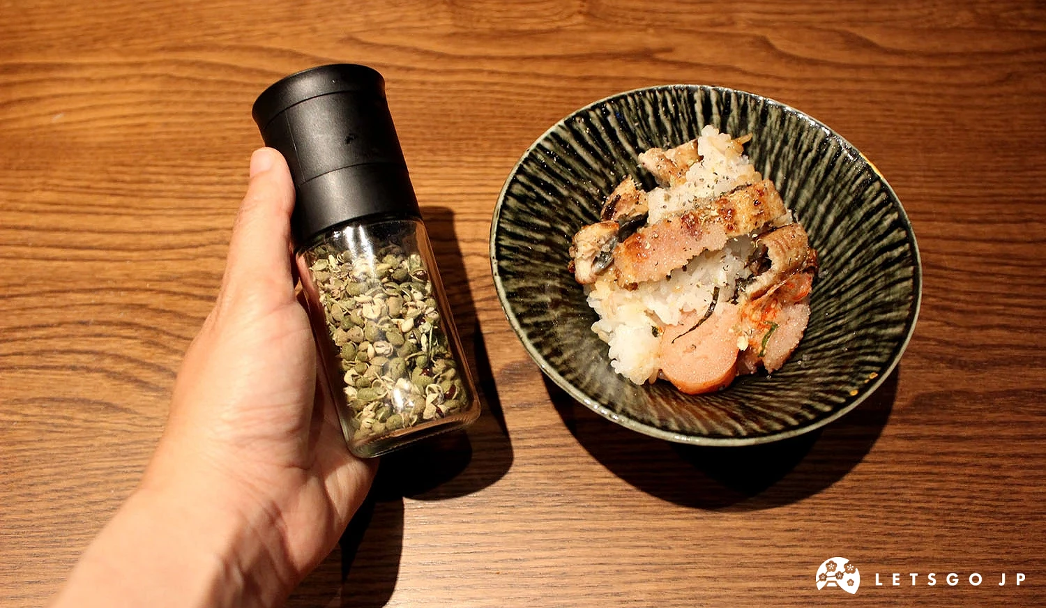手持裝著山椒的玻璃罐,與盛裝到碗裡的「明太子白燒鰻魚釜飯」