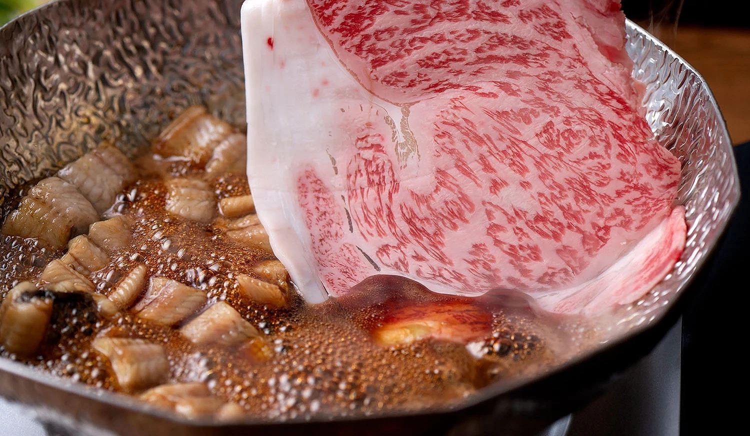 和牛肉片與在鍋內的醬汁鰻魚