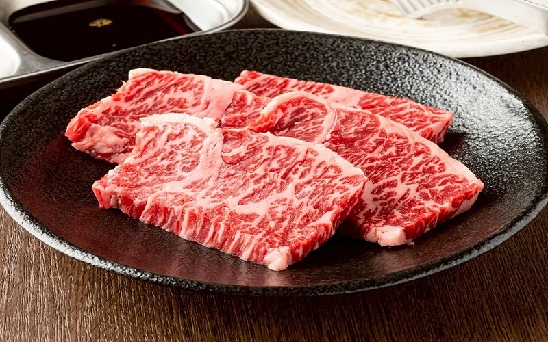 四塊大理石油脂紋路牛橫隔膜肉片盛於黑色橢圓盤