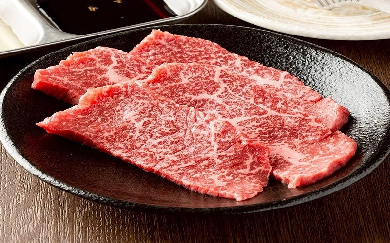 三片大面積和牛里肌肉,油花分布均勻,盛於黑色橢圓盤