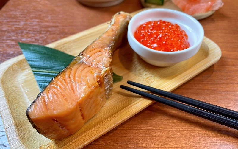 竹盤上盛烤鮭魚一切,旁附一碗鮭魚卵