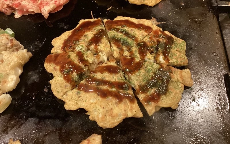 鐵板上烤好的大阪燒淋上醬汁與青海苔,已切成數份