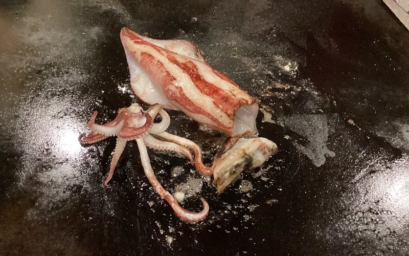 整尾小卷與腳爪在黑色鐵板上煎烤中