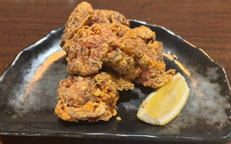 黑盤盛炸雞塊,旁附一片檸檬