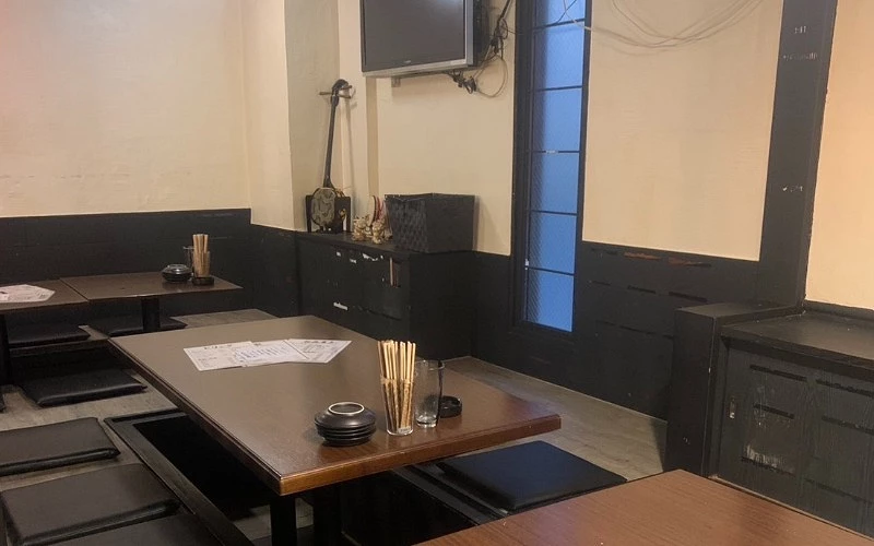 居酒屋內和式座位,牆上掛電視與三線琴