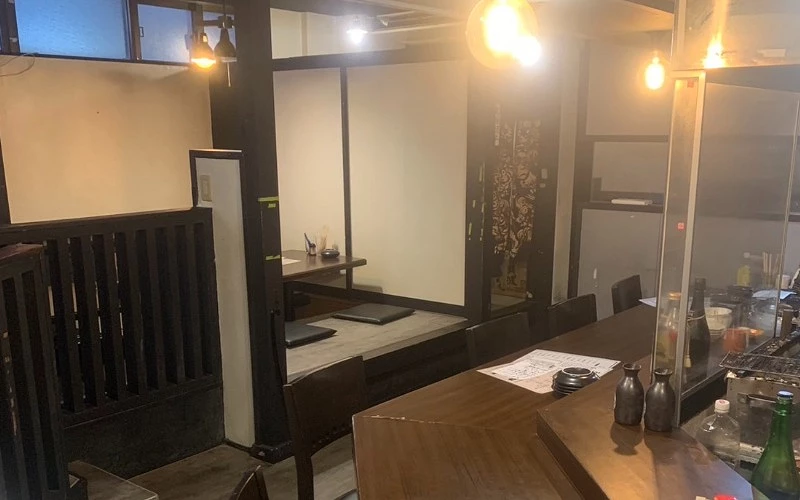 居酒屋內部,暖色吊燈下有下嵌式座位與桌椅