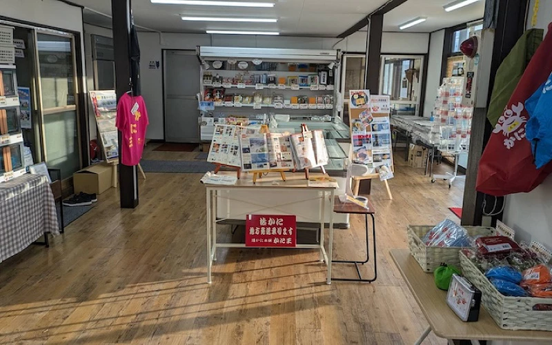 店內伴手禮區陳列櫃與商品,掛有粉色T恤