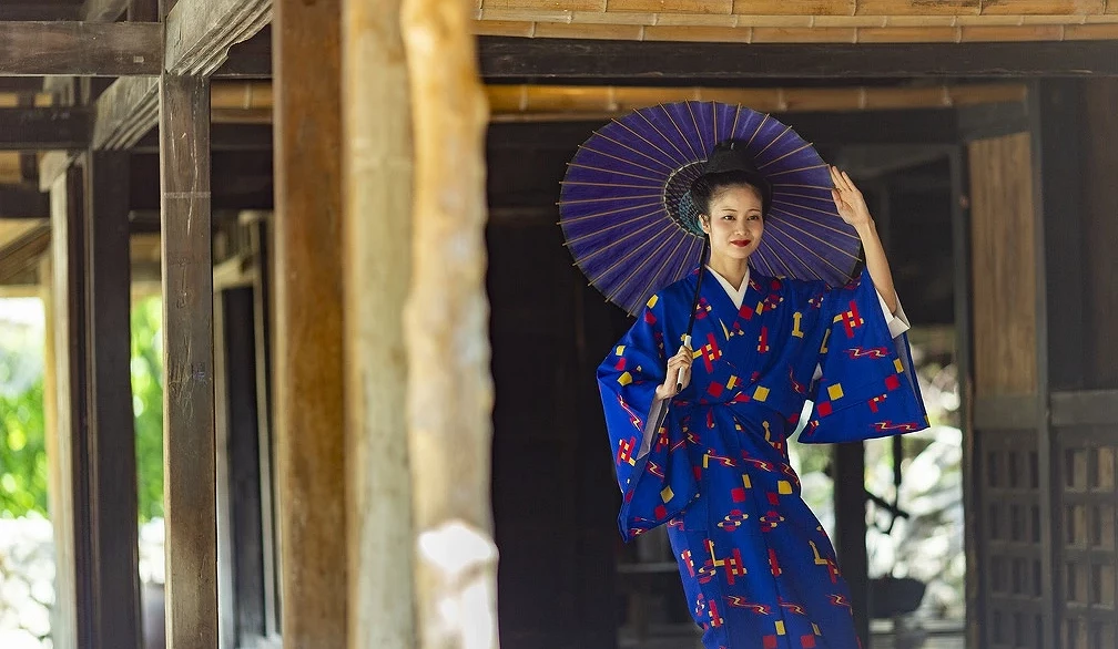 琉球村藝能秀表演者身穿琉球傳統服飾,手持和傘在古民家內演出琉球舞踊