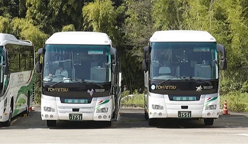 有兩台白色的巴士並行停著,車頭朝前面。