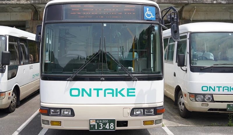 有三台巴士並列排著,白色的巴士上用水藍色寫著「ONTAKE」的字樣。