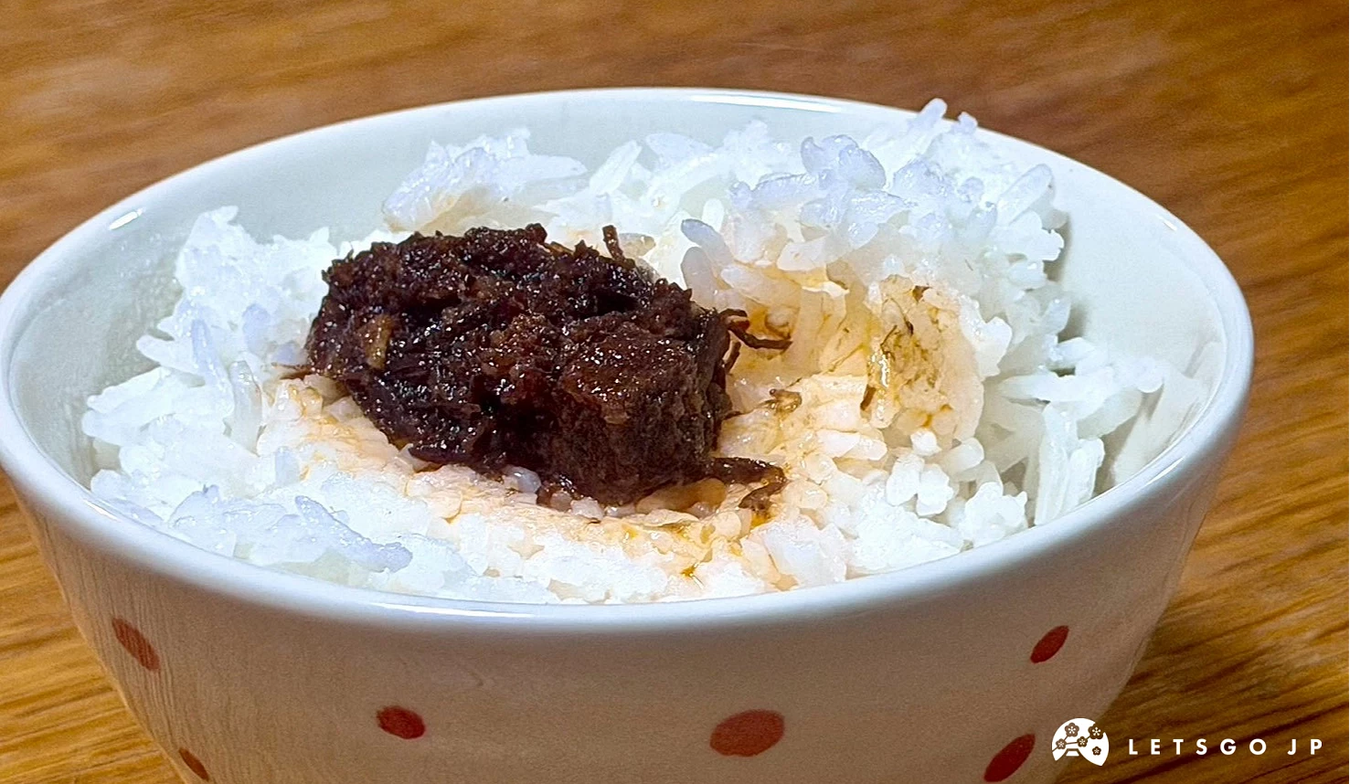 裝有白飯的紅點白碗,上方放有深褐色肉塊醬料