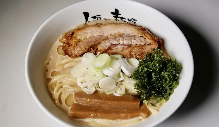 一碗白色湯頭的拉麵,上面有肉片、筍乾跟蔥花。