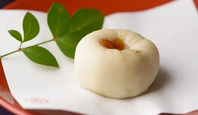 白色大福置於紅盤,綠葉裝飾點綴,傳統日式點心精緻優雅。