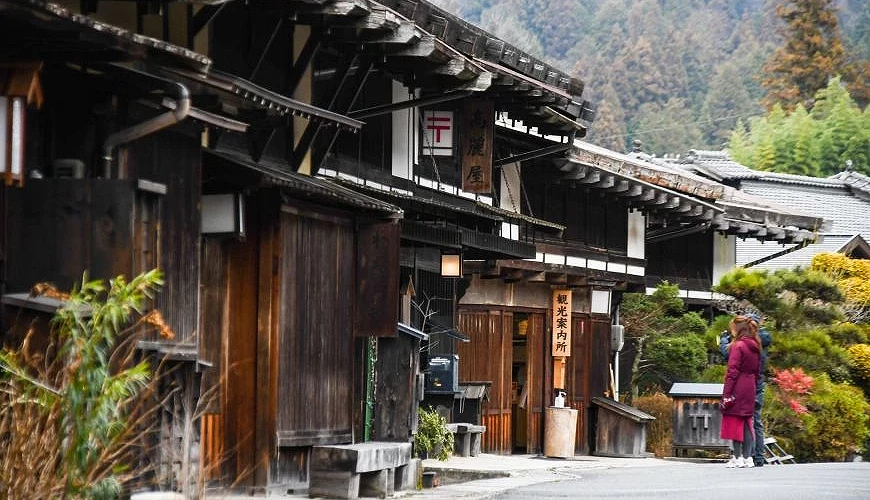 一條道路,左邊是日式傳統房屋建築,道路上站著一個人。
