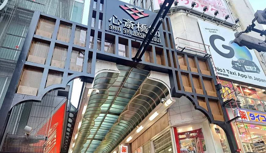 上面寫著「心齋橋」字的牌子,下面是一條商店街。