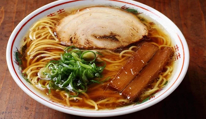 一碗醬油拉麵,上面有一片肉片跟蔥花。