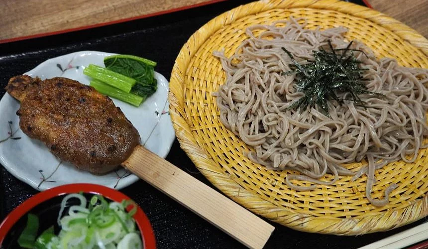 盤子上有蕎麥麵,左邊有一串五平餅,還有一小盤蔥花。