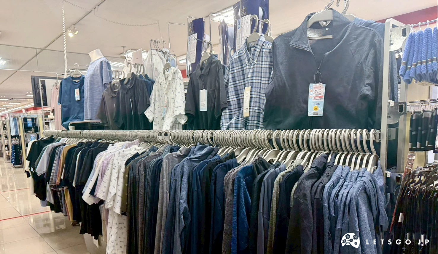 服飾店內吊掛著整排深藍色、格子圖案與大地色系的男士長袖襯衫與外套衣架。