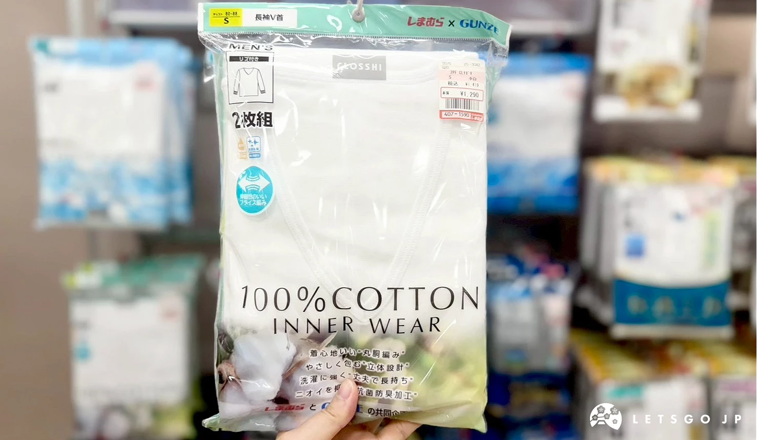 一隻手在店內拿起展示的一包綠色包裝「100% COTTON INNER WEAR」純棉男女內著衣。