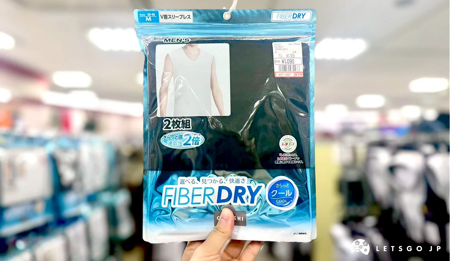 一隻手在賣場內拿起展示的一包包裝印有「FIBER DRY」水藍色標籤的涼感內搭背心。