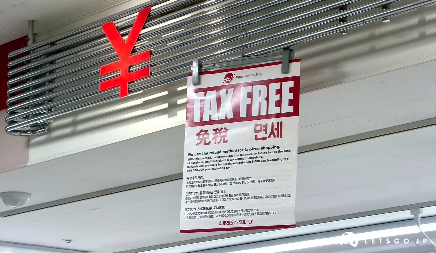 天花板金屬管上掛著寫有紅色「TAX FREE 免稅 免세」的四國語言退稅告示牌,旁邊有紅色百分比符號。