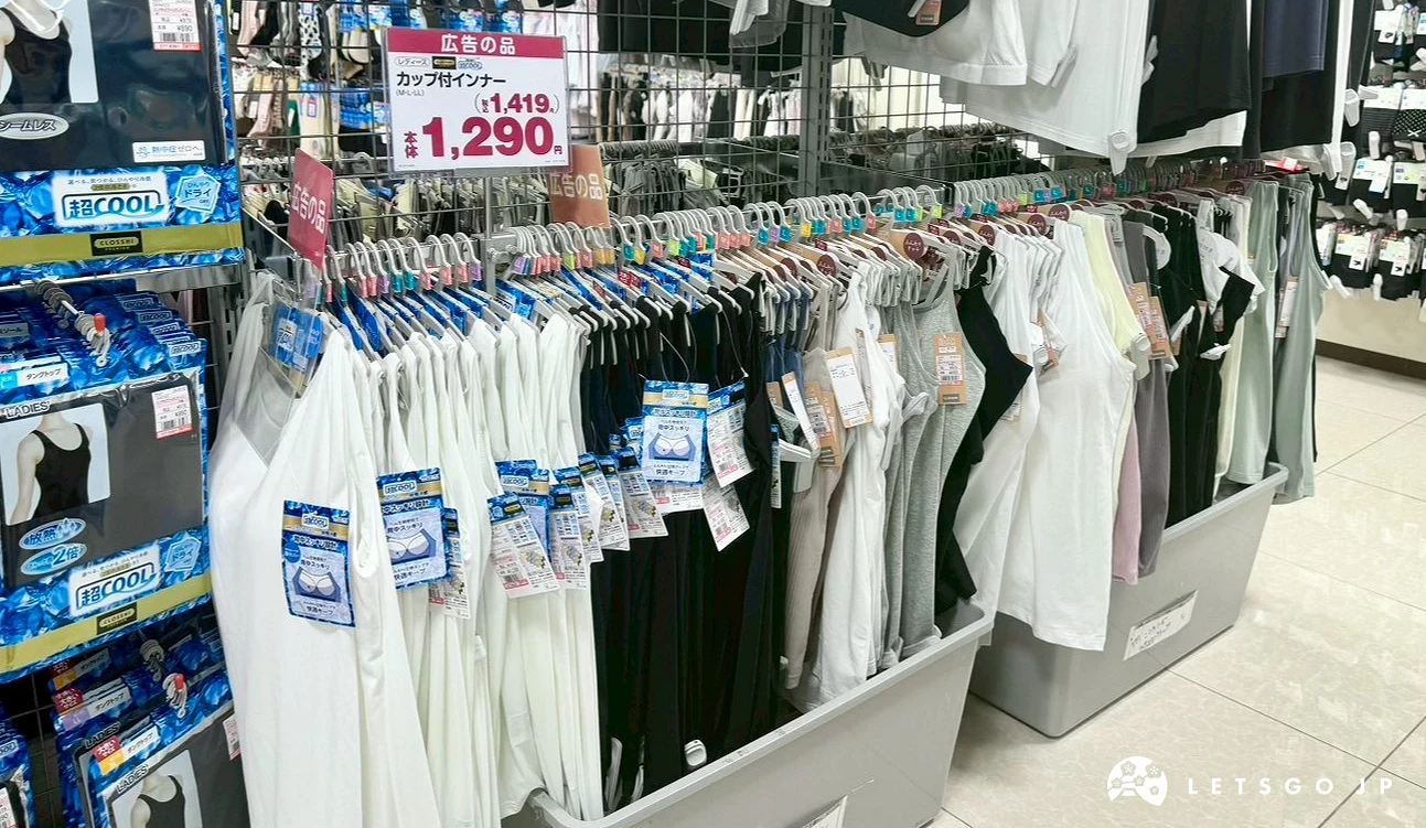 掛滿了黑色、白色等特價機能內搭的服飾陳列架,上方標示著 1,290 日圓的價格。