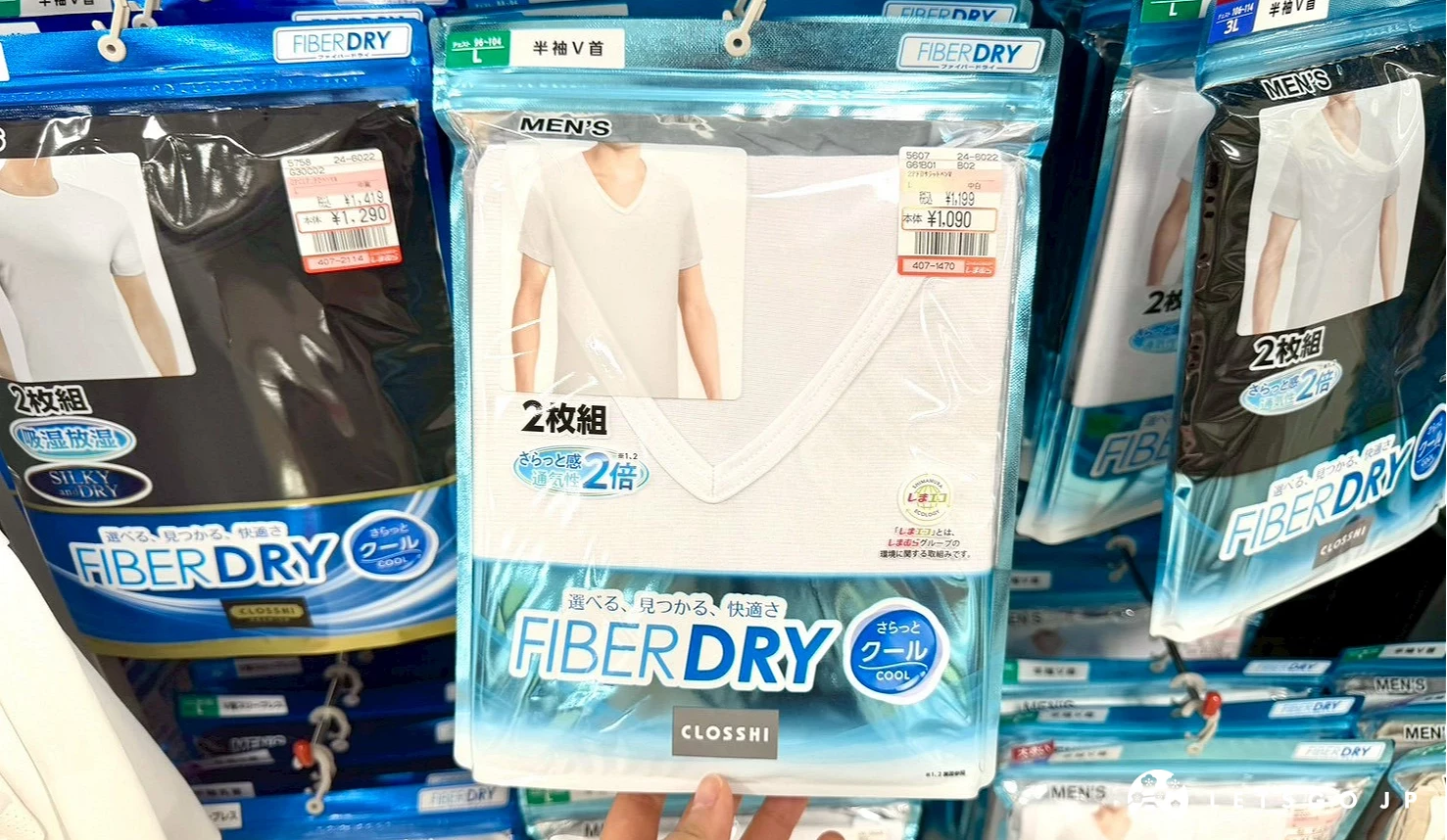 雙手拿起展示的一包包日本思夢樂「FIBER DRY」系列吸汗速乾男士白色V領內搭衣。