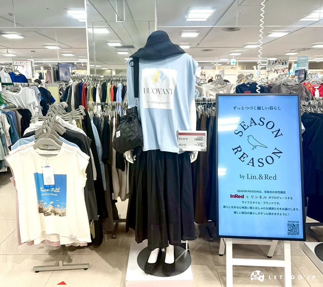 日本思夢樂服飾店內展示的黑色長裙與白色上衣女裝模特兒,旁邊立著「SEASON REASON」藍色聯名品牌廣告牌。