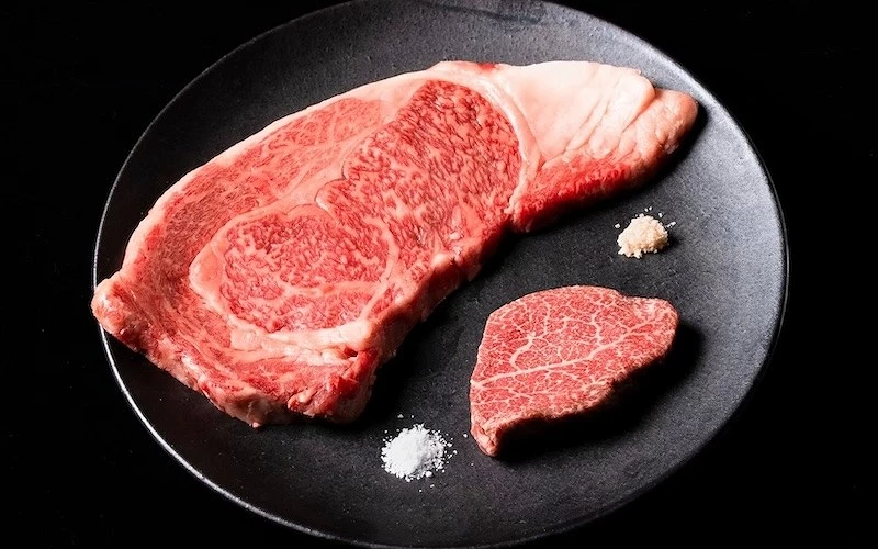 黑色圓盤盛大塊和牛里肌與小塊菲力，旁附兩堆岩鹽