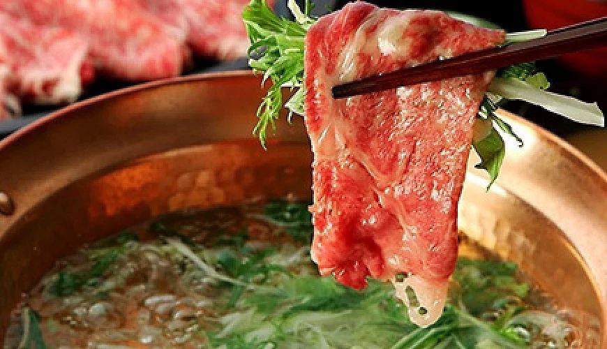 筷子夾起涮肉片與蔬菜