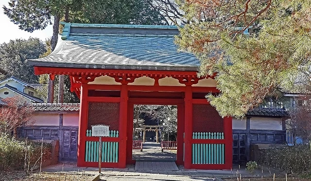 日本埼玉縣川越仙波東照宮朱紅色隨身門(國指定重要文化財)外觀,透過門洞可望見後方的石造鳥居與綠意樹林