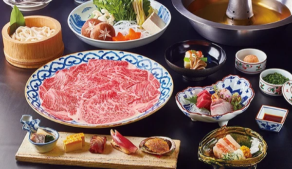 壽喜燒套餐,有一盤生牛肉片、一盤青菜和一碗烏龍麵、生魚片小菜