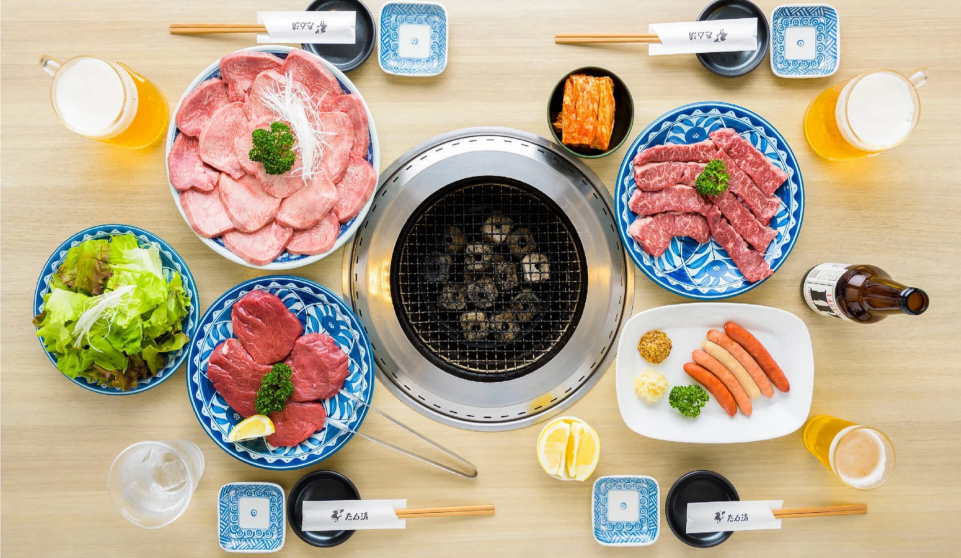 燒肉套餐。中間有一個烤盤,旁邊有生菜、燒肉跟泡菜,還有啤酒。