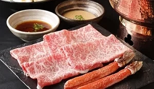 一套套餐,有牛肉片和蟹腳,旁邊有兩碗沾醬。