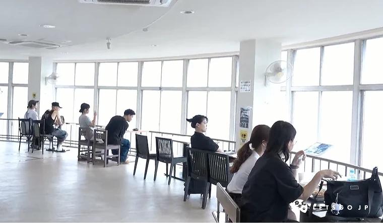 山頂餐廳寬敞明亮,白色天花板與大落地窗,黑色椅子與餐桌,遊客用餐欣賞景觀,白色牆面與淡色地板,現代簡潔設計風格。