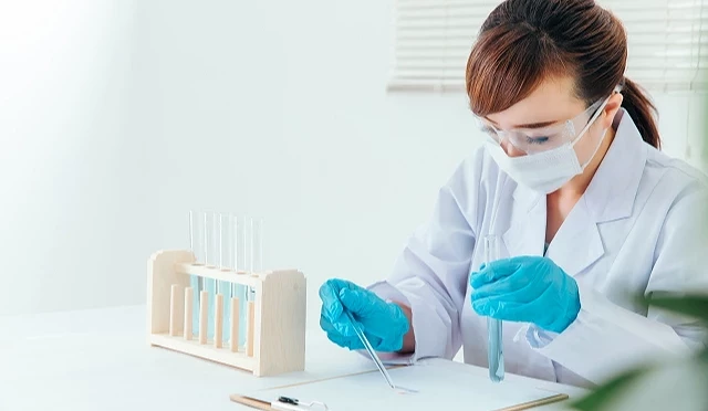 戴著護目鏡、口罩與手套的研究人員操作試管並記錄實驗資料