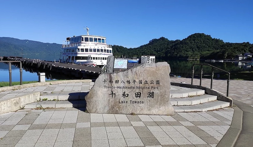 十和田湖石碑,後面停著一艘白色遊船