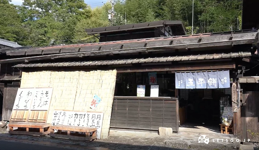 傳統木造日式建築店面,掛有寫著「五平餅」字樣的藍色暖簾,左側立有寫有日文標語的看板