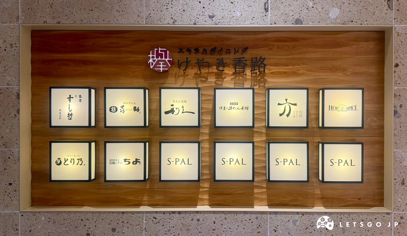 「櫸樹香路(けやき香路)」深色木紋告示牆,上面鑲嵌著數個燈箱,顯示進駐的牛舌與壽司名店名稱。