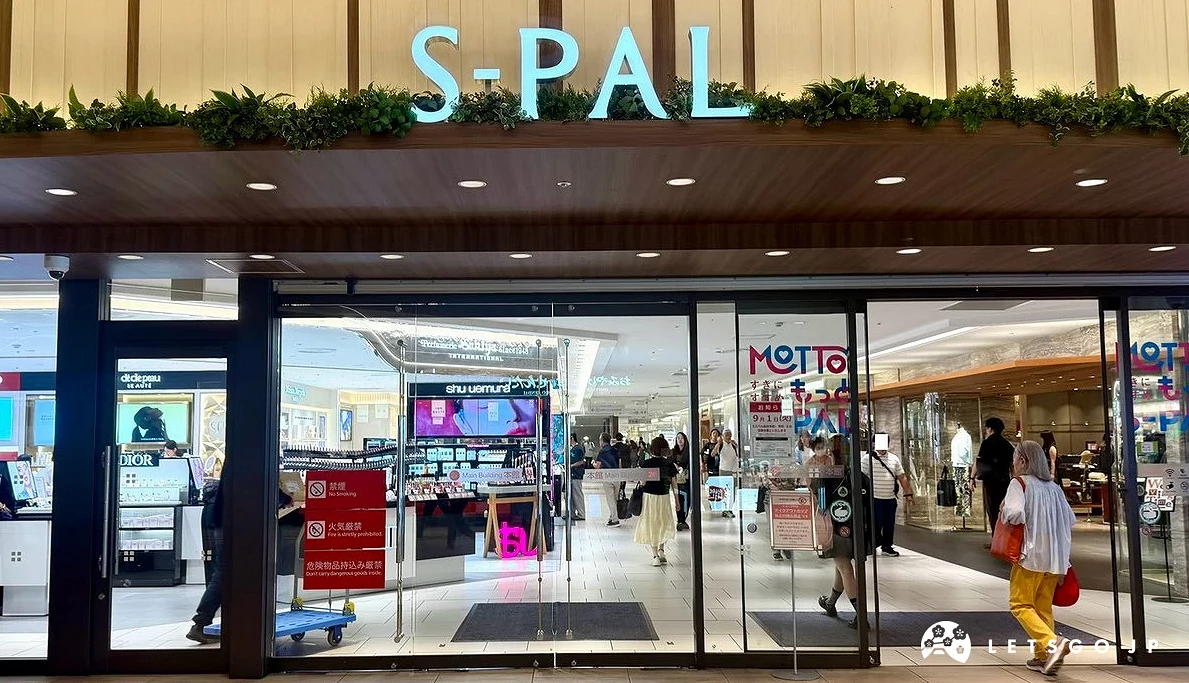 S-PAL 商場的另一處玻璃門入口,頂部懸掛帶有綠植裝飾的「S-PAL」白色字樣標誌,門內光線明亮。