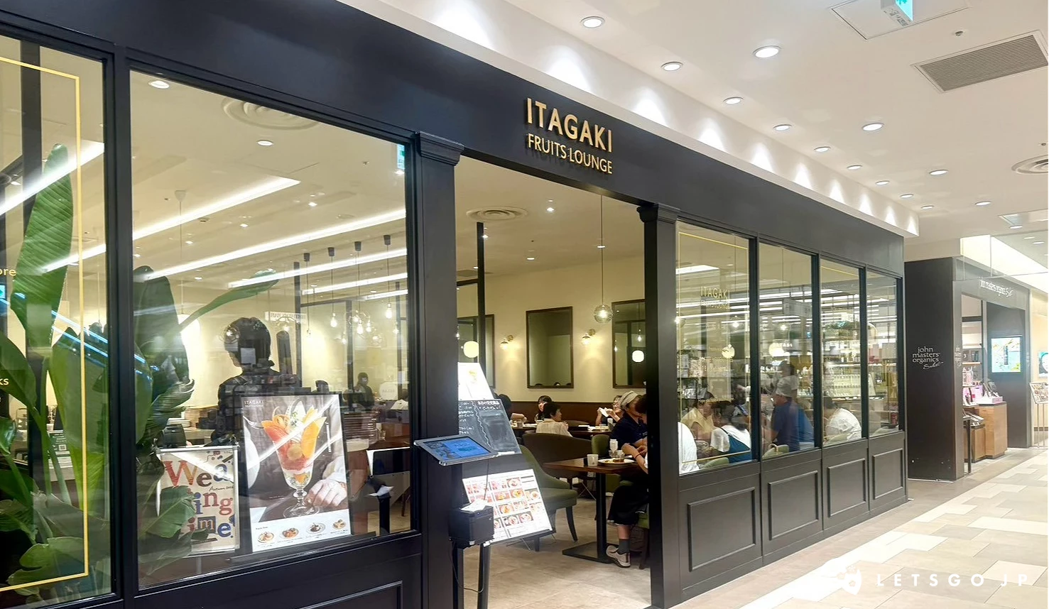 「ITAGAKI FRUITS LOUNGE」咖啡廳的黑色典雅店面外觀,透明玻璃窗可透視內部溫馨照明與用餐顧客。