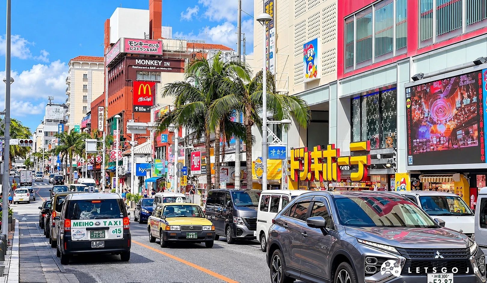 街道兩側有棕櫚樹與麥當勞、唐吉訶德招牌,計程車及多輛汽車行駛於道路上,天空晴朗。